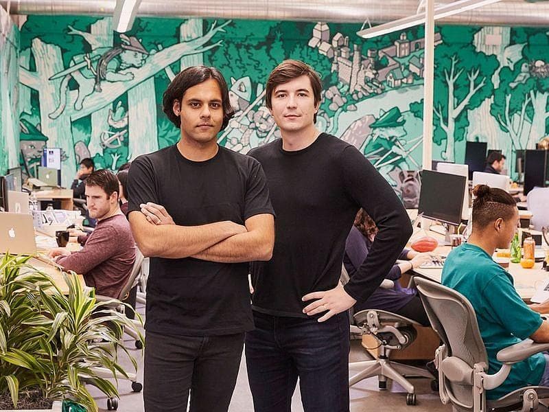 Robinhood co-founders Baiju Bhatt and Vladimir Tenev in their Palo Alto office, in front of a green forest mural.